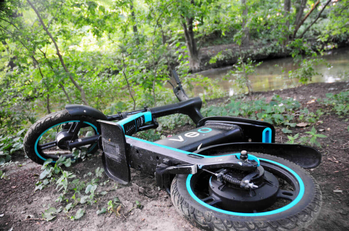 seated e-scooter in dirt in front of river