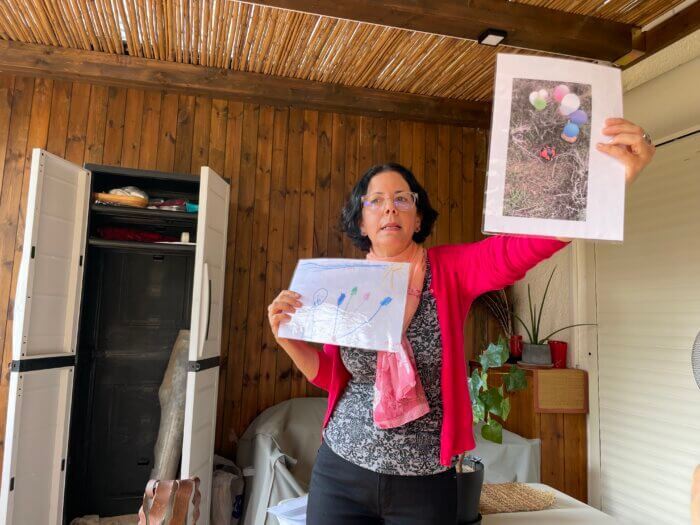 A tour guide holds up pictures kids drew at the Kibbutz Kfar Aza in Israel in December 2022.