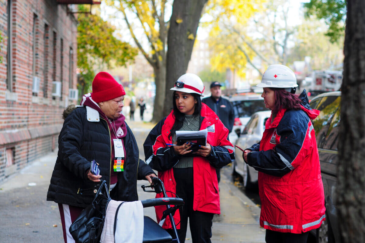 Cynthia Aikens, a resident of 2309 Holland Ave., is assisted by Sofia Manzi and Lenore Grogan of the American Red Cross after a fire at her apartment building on Friday, Nov. 17, 2023. Aikens lost everything in the blaze that killed one tenant and injured five others.