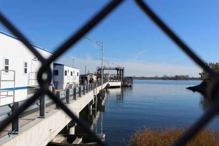 Officials wait on the ferry dock in City Island. Hart Island, in the background, is accessible from the dock by ferry.