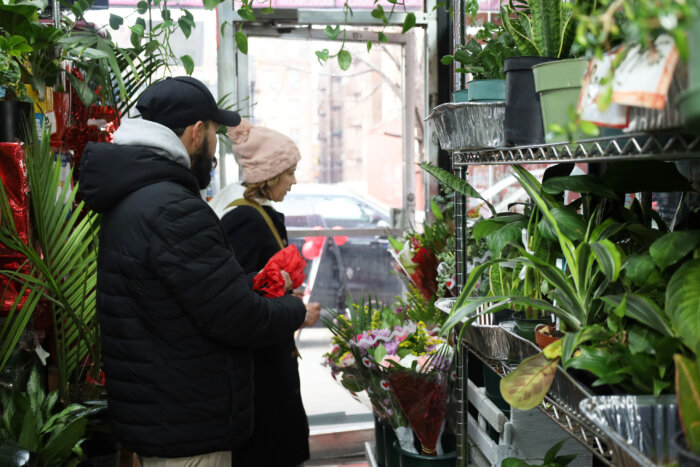 Jorge Corona, son of Lucila, proprietor of Lucy's Flower Shop at 2655 Jerome Ave., helps a customer at his mother's 28-year-old business on Thursday, Dec. 7, 2023. 