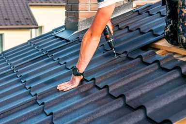 a professional master (roofer) with electric screwdriver covers repairs the roof