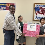 Two student representatives from Saint Barnabas High School hold a box of socks to donate to veterans.
