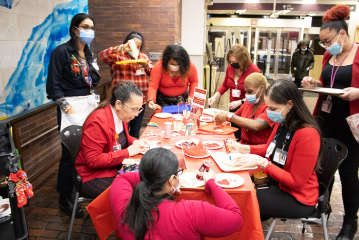 Attendees — including Cibele Vieira, artist in residency from the creative center — and NYC Health + Hospitals North Central Bronx staff members create art and wear red in honor of National Wear Red Day.