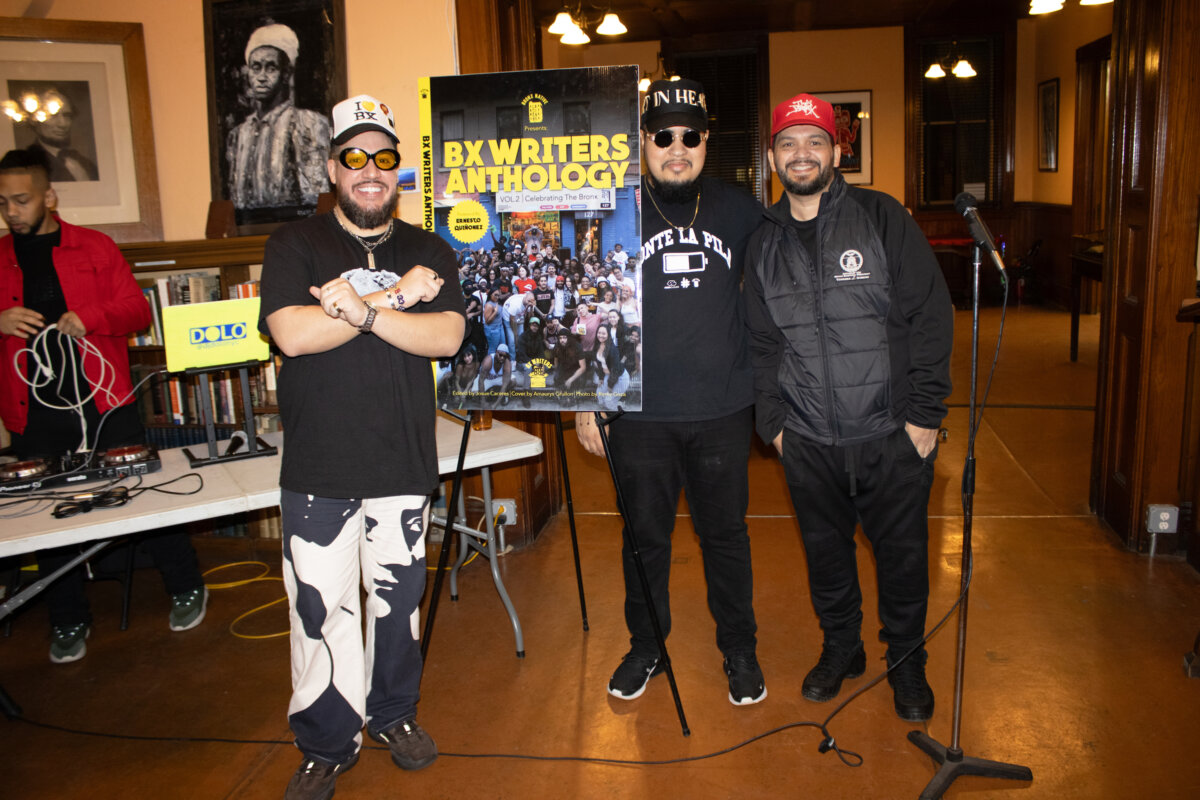 A group photo in front of the BX Writers Anthology banner with Amaurys Grullon, founder and CEO of Bronx Native; Josué Caceres, founder and CEO of BX Writers; and Angel Hernandez, president of Huntington Free Library.