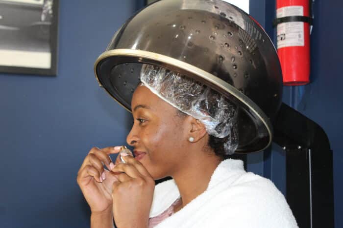 Kerene Edie sits under the dryer at Hair By Dee in Van Nest on Tuesday, Feb. 20, 2024.