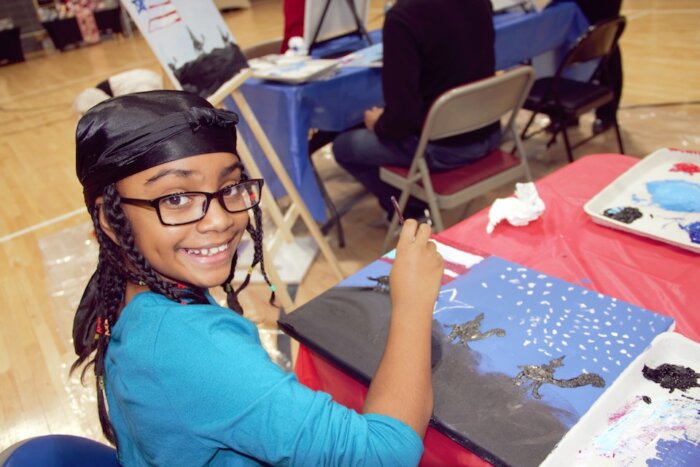 A young girl paints the three kings on canvas at the Bronx Puerto Rican Day Parade’s relaunch event.