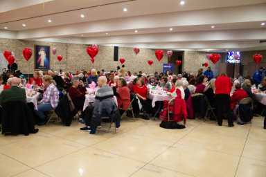 Seniors sitting at their tables enjoy the festivities, eating and more.