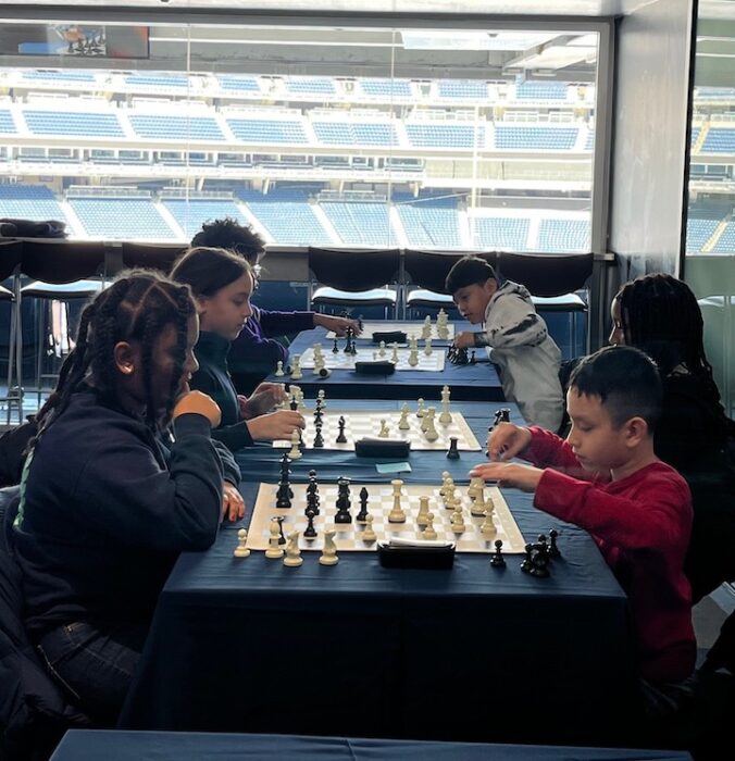 Students play chess near a window overlooking the field at Yankee Stadium.