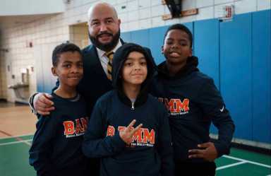 Three students stand with Councilmember Rafael Salamanca at the youth input session.
