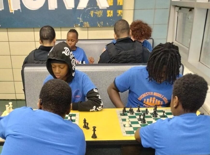 Baychester Middle School students play chess with officers from NYPD’s