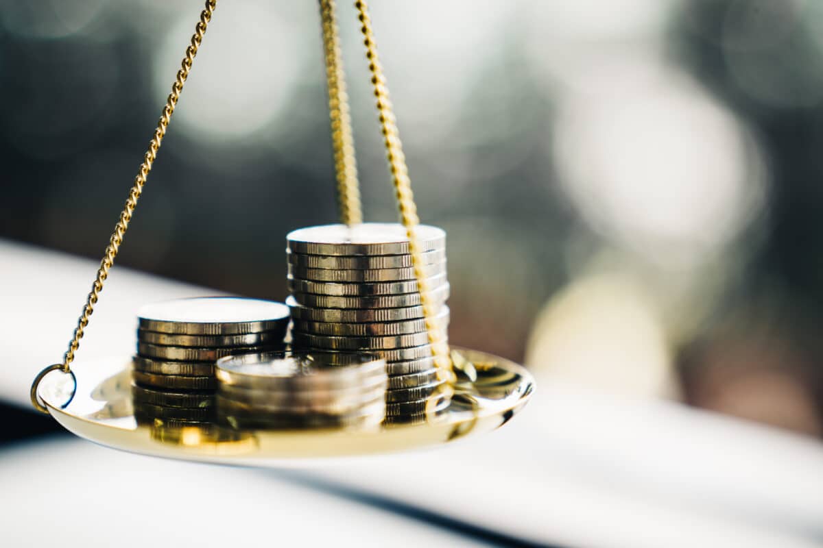 Coins stack on a balance scale.