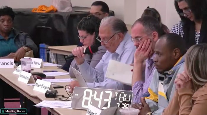 CB11 board member Phyllis Nastasio hands in her letter of resignation during a chaotic full board meeting on Thursday, April 25, 2024.