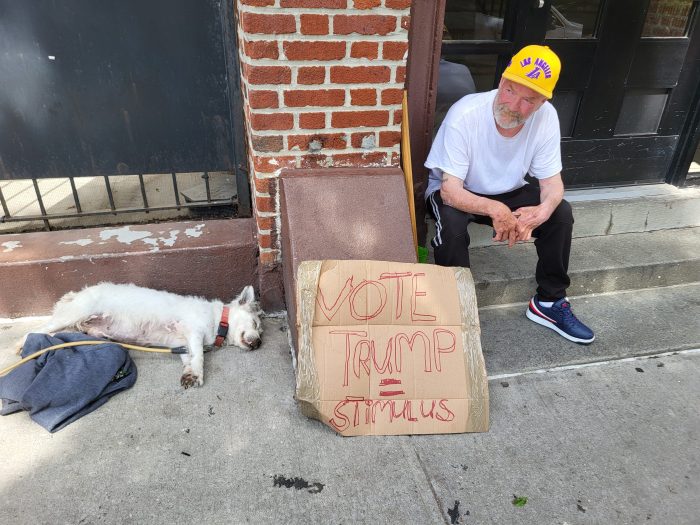 Bronx resident Lawrence Gannon sits with a sign of support for Donald Trump during the day of the former president's campaign rally in Crotona Park on May 23, 2024.