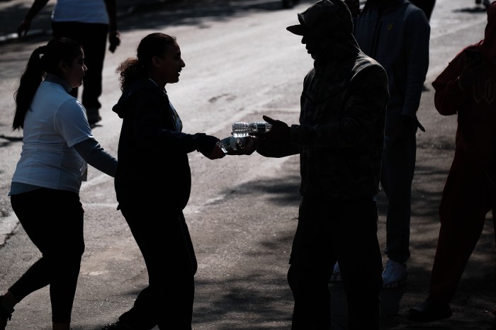 Bronx residents hand free water bottles to runners during the 46th Annual Roscoe C. Brown Jr. Hall of Fame 10K.