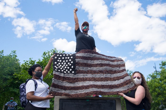 Tasha Dougé (center) protests the death of George Floyd with "This Land is OUR Land."