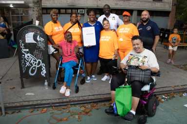 A group photo with Community Council President, Barabara Holmes; Moore House Resident Association members; Bronx Borough President, Vanessa Gibson holding a Proclamation recognizing August 6 as National Night Out; PSA7 Commanding Officer Kwo; Council Member Rafael Salamanca; and Dana Elden, St. Mary's Park Houses Resident Council.