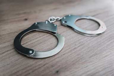the concept of arrest and crime. handcuffs on a wooden table