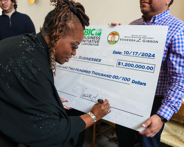 Bronx Borough President Vanessa L. Gibson signs a giant commemorative check for $1.2 million in loans to Bronx small businesses.