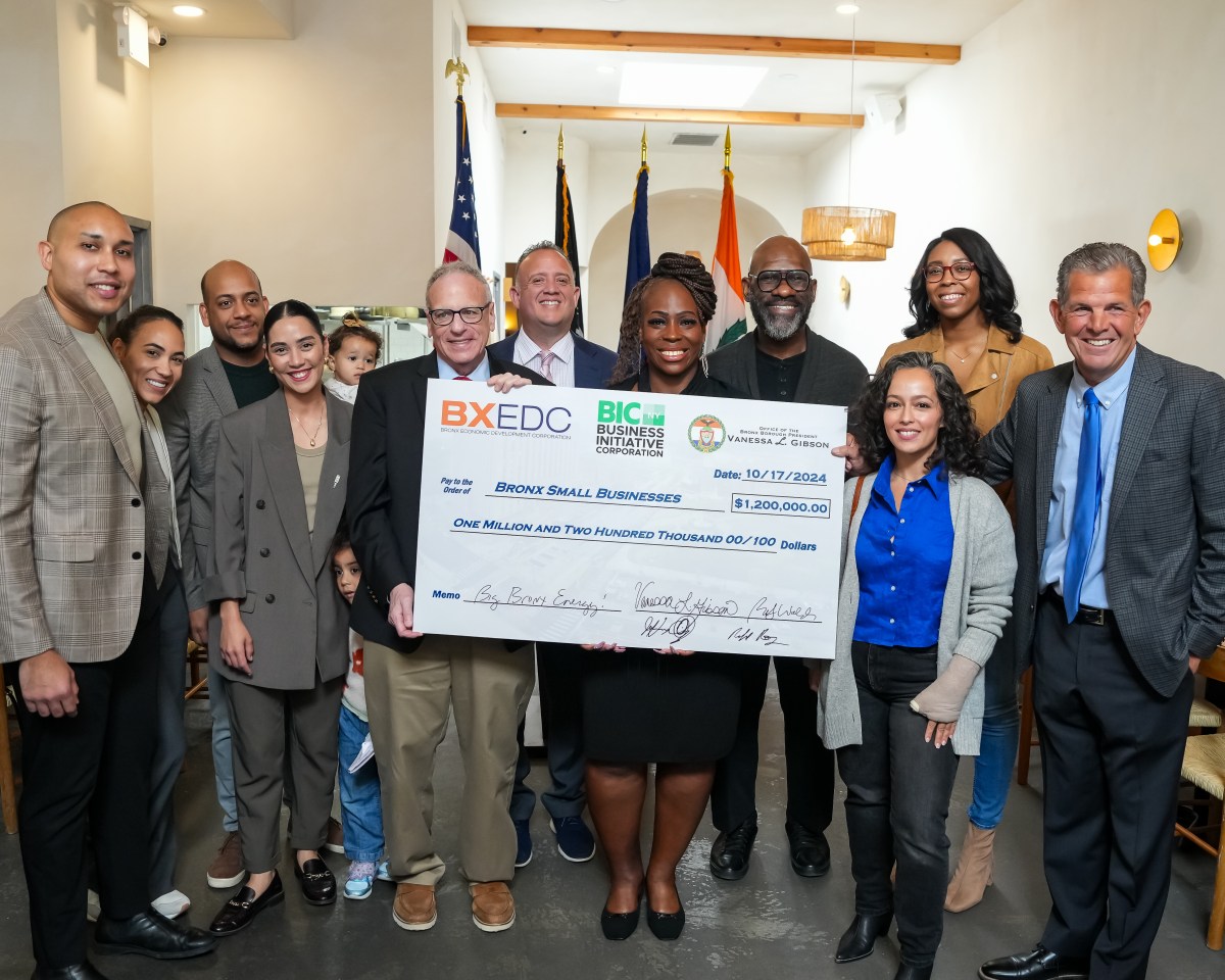 Officials and small business owners stand behind a giant commemorative check for a small business loan program.