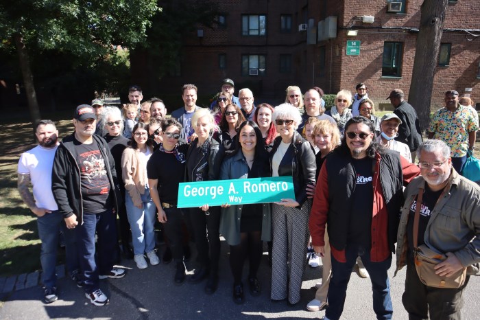 A crowd gathers around the street sign for the intersection co-named for filmmaker George A. Romero.