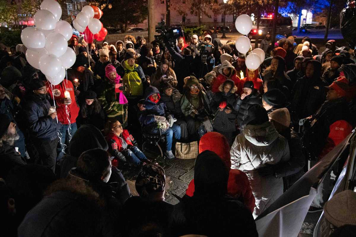 A Bronx football team gathered in a semicircle holding candles and balloons to honor their beloved coach after his sudden death, Dwight Downer.