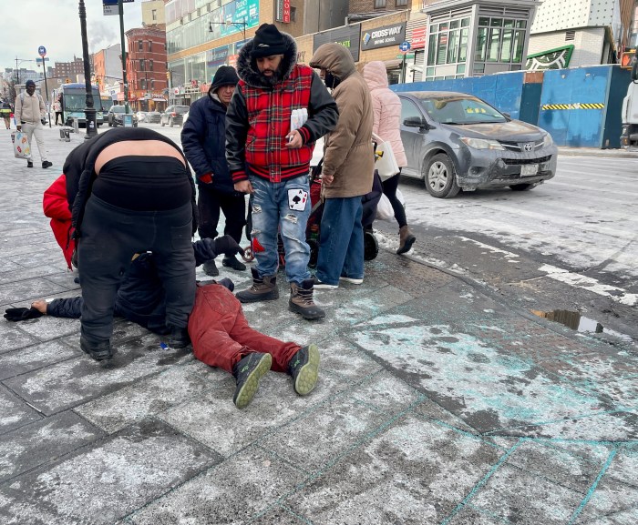 Concerned people try to communicate with a man who lay face down on the sidewalk on the coldest day in NYC in years.
