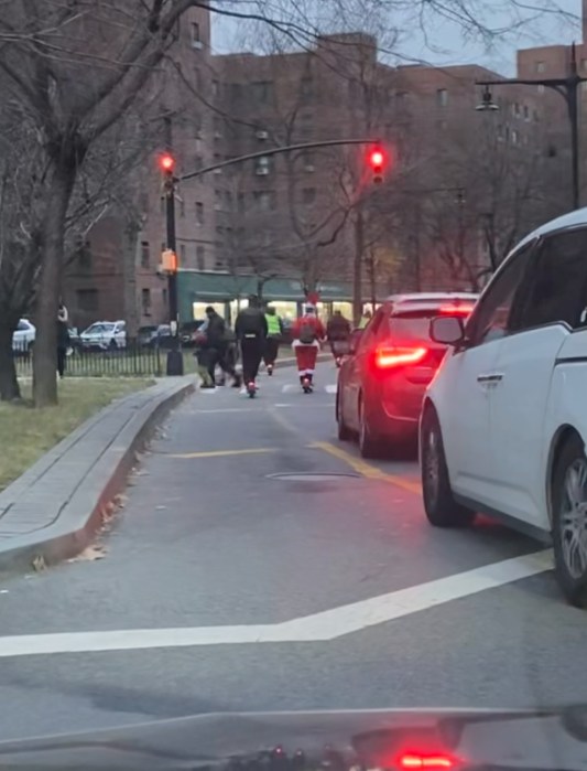 Council Member Marmorato's office sent the Bronx Times a live photo of e-scooter riders in holiday garb nearly striking a family in a cross-walk while running a red light. 