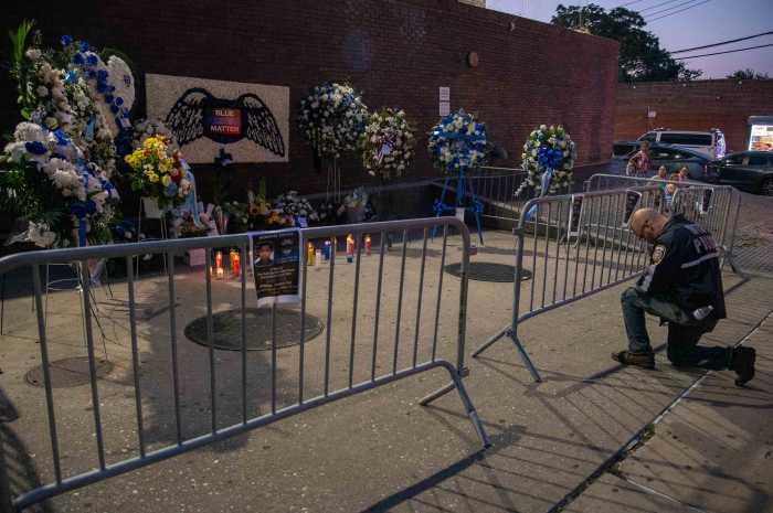A NYPD officer knelt in prayer in front of the memorial honoring the slain detective outside the 47th Precinct where he served for three-and-a-half years.
