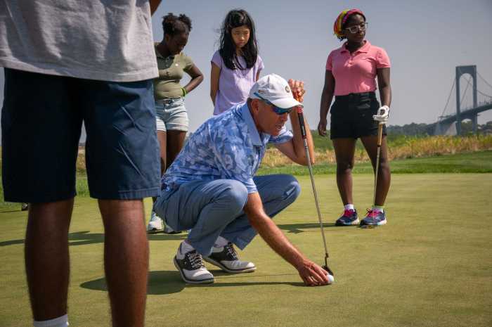 Bally's Ferry Pont PGA Professional Coach Mal Galletta, with over 31 years of coaching experience, shows young golfers at the junior clinic how to size up a putt and take measure of the speed, alignment and aim needed to sink a putt.