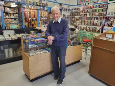 man smiling at counter of record store featured in Vinyl NYC