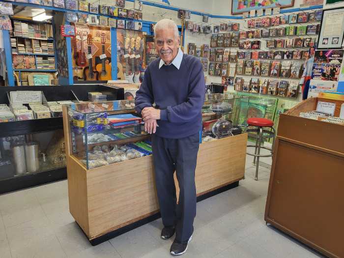 man smiling at counter of record store featured in Vinyl NYC