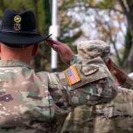 United States Army Warrant Officer (left) and U.S. Army Chief Warrant Officer David Wray (right) salute as a trumpet player blows out "Taps," honoring those who died serving their country for the Bronx Veterans Day Parade.