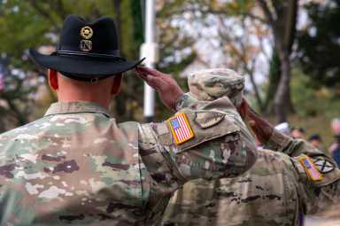 United States Army Warrant Officer (left) and U.S. Army Chief Warrant Officer David Wray (right) salute as a trumpet player blows out "Taps," honoring those who died serving their country for the Bronx Veterans Day Parade.