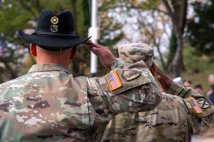 United States Army Warrant Officer (left) and U.S. Army Chief Warrant Officer David Wray (right) salute as a trumpet player blows out "Taps," honoring those who died serving their country for the Bronx Veterans Day Parade.