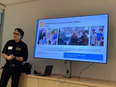 Anthony Carrión in front of a screen describing the benefit of joining a Neighborhood Advisory Board.