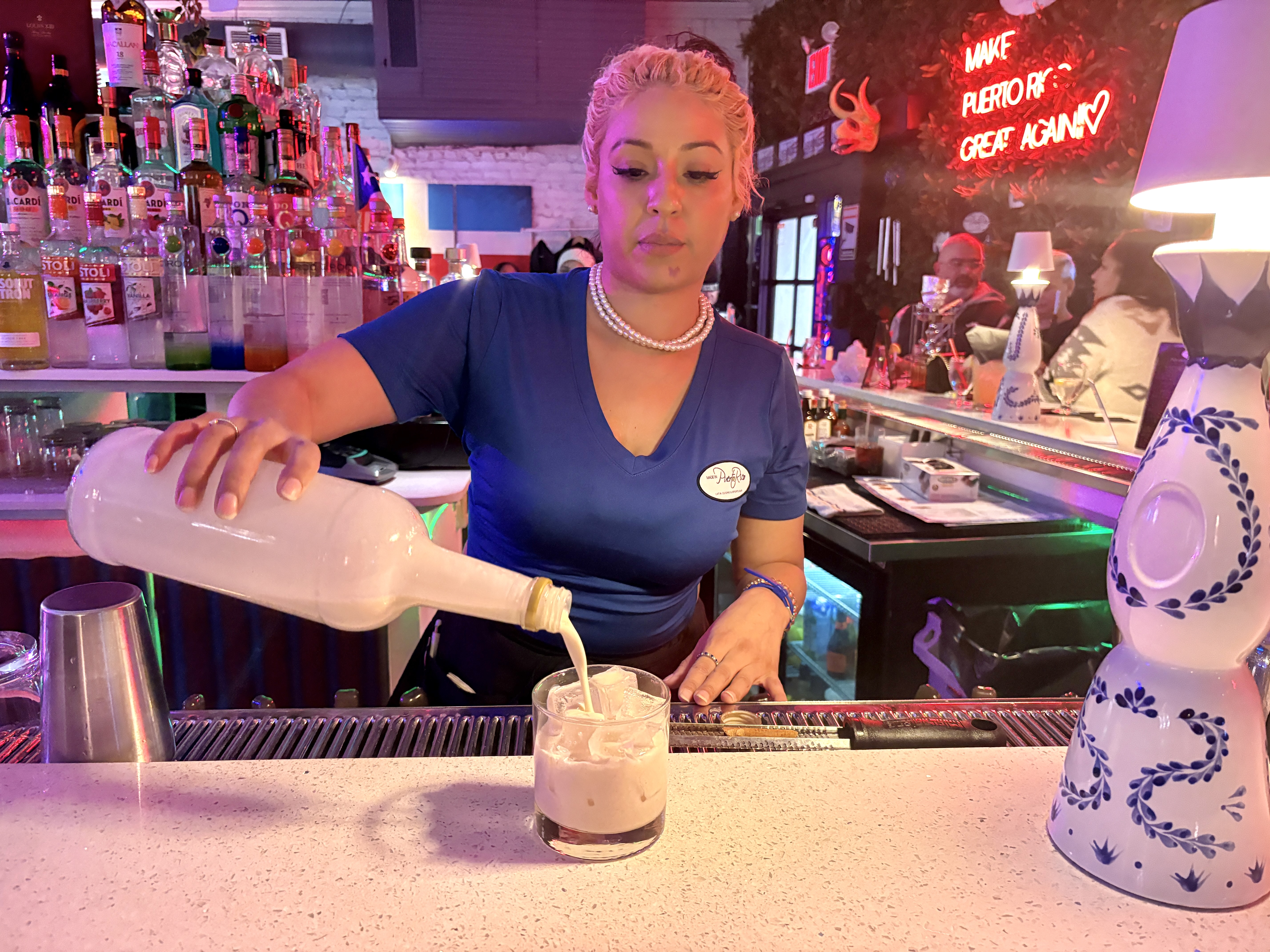 A bartender at Throggs Neck's Made in Puerto Rico, pours a glass of homemade coquito, made with fresh ingredients and the Puerto Rican rum Don Q.