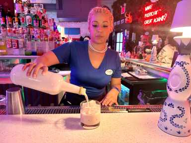 A bartender at Throggs Neck's Made in Puerto Rico, pours a glass of homemade coquito, made with fresh ingredients and the Puerto Rican rum Don Q.