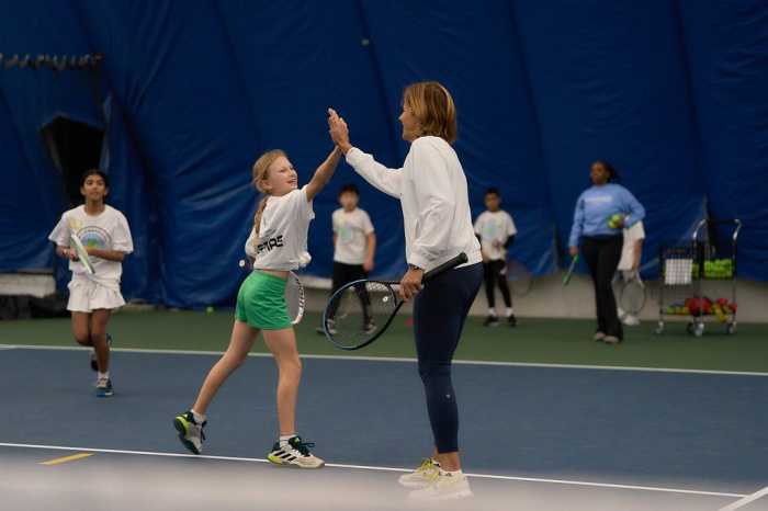 Tennis Hall of Famer Gigi Fernández high fives a young tennis player at the Cary Leeds Center for Tennis and Learning on Sunday. Fernández and fellow tennis legend Tracy Austin helped young players with their skills and offered wisdom on how to maintain the discipline and drive to become an incredible athlete.