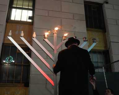 A Rabbi lights a menorah in front of Chabad of South Bronx during Hanukkah.