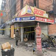 Workers remove the charred debris from Fane Grocery after the Saturday morning fire.