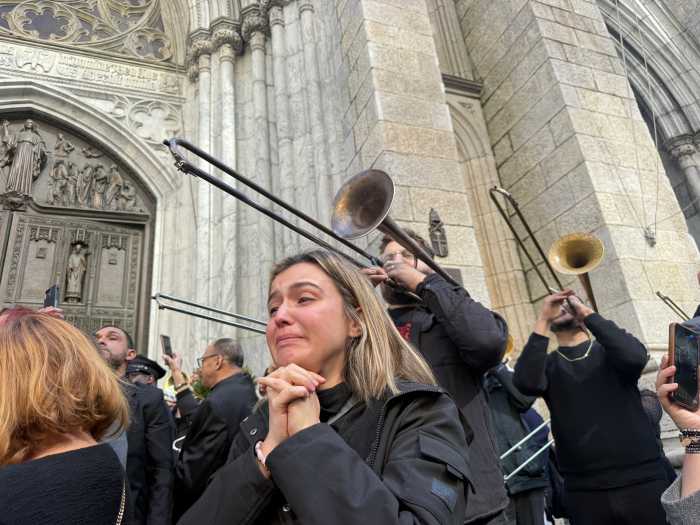 Fans tear up as pallbearers bring the casket of Willie Colón down the steps, as trombonists play 'La Murga.'