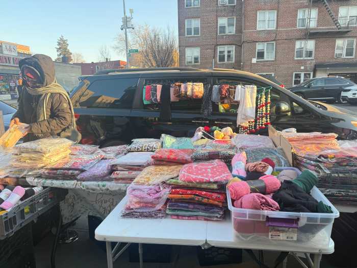 Vendors display stacks of salwars for sale.