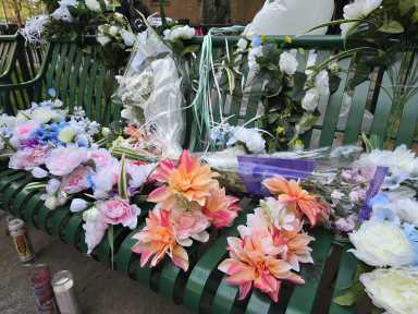 Flowers, garlands, and candles lay on the bench where 78-year old Edgar Spence was killed by a stray bullet on Thursday.
