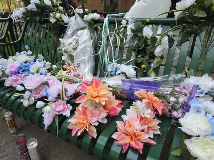 Flowers, garlands, and candles lay on the bench where 78-year old Edgar Spence was killed by a stray bullet on Thursday.