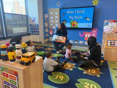 Three teachers at BronxWorks leading story time for a mixed-age group of children.