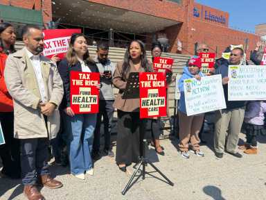 Assemblymember Amanda Septimo speaks out against the Essential Plan cuts at the Tax the Rich rally, alongside State Sens. Jose Serrano and Kristen Gonzalez.