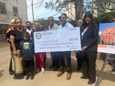 Rep. Ritchie Torres presents residents of Concourse Village with a ceremonial check to be put towards pipe replacement.
