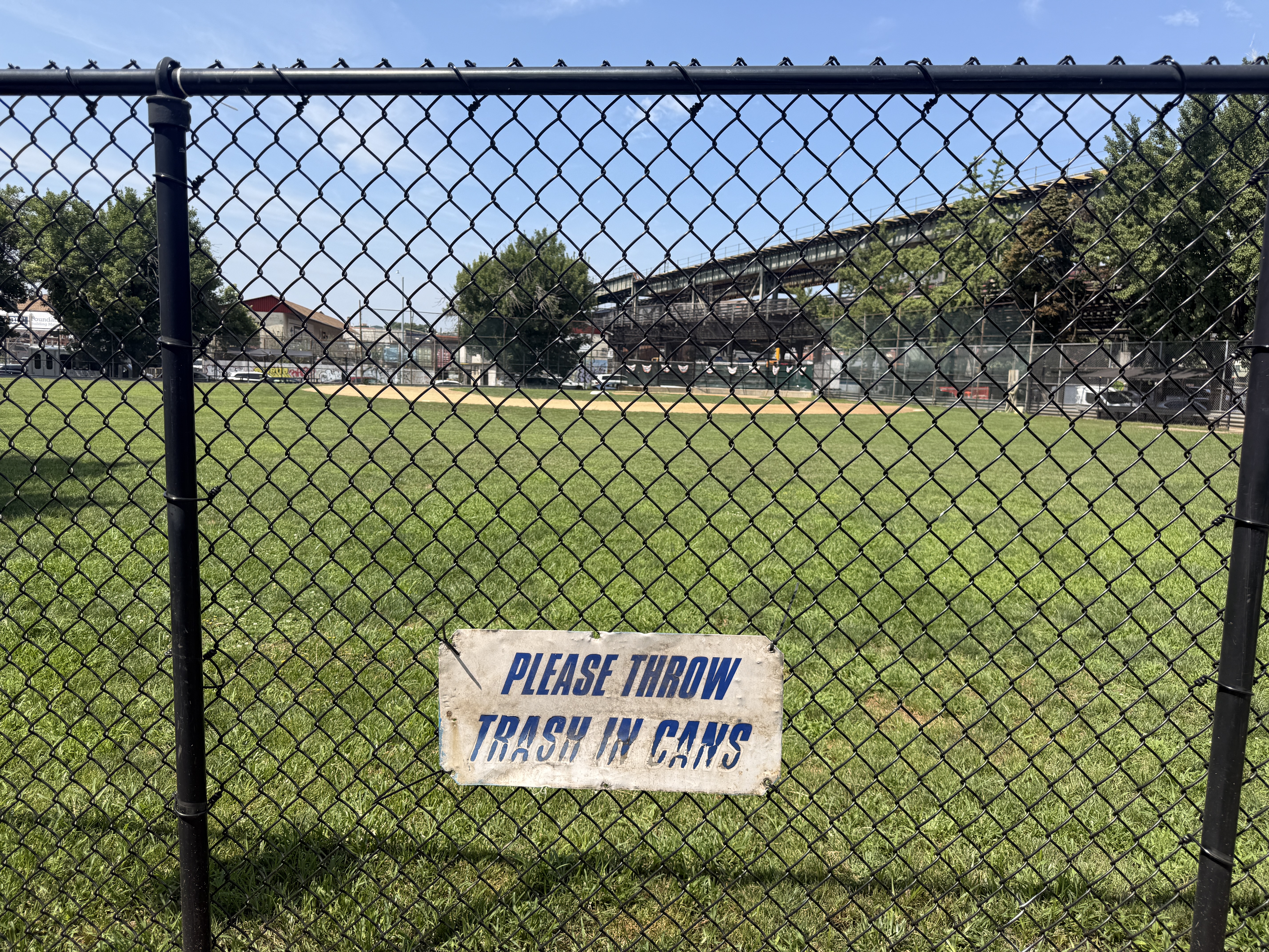 Anti-littering signs are placed along the inner fencing of the Pelham Bay Little League field.