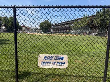 Anti-littering signs are placed along the inner fencing of the Pelham Bay Little League field.